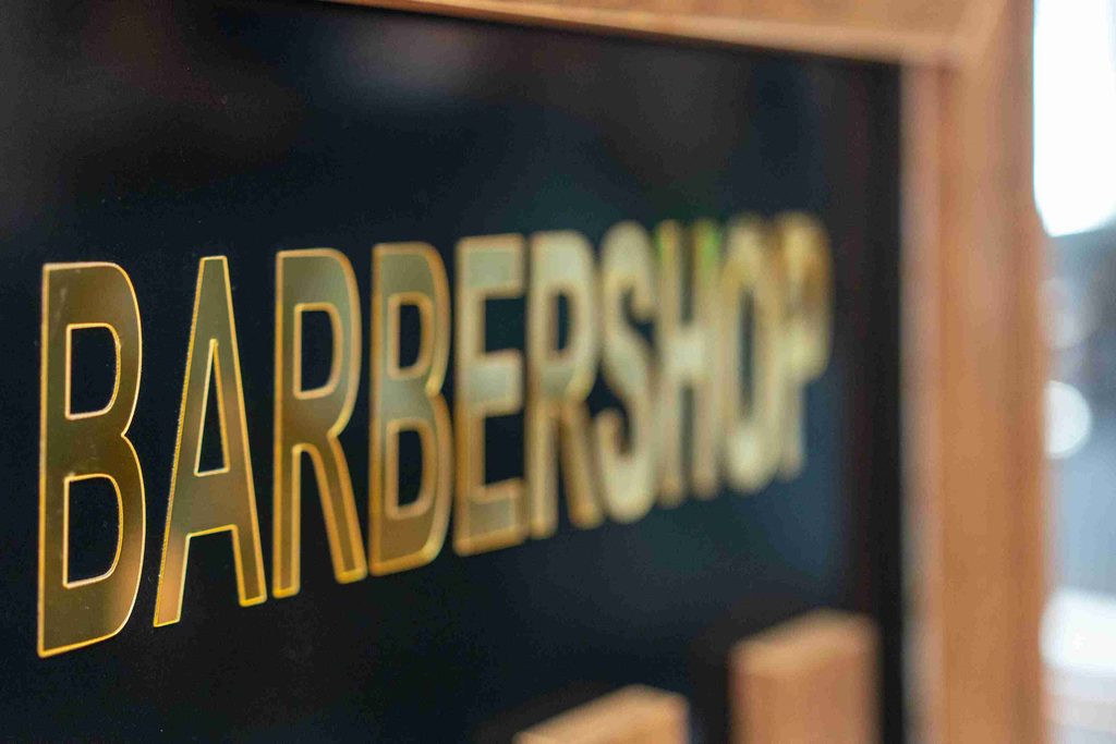 A classic barber shop sign featuring red, white, and blue stripes, indicating a place for haircuts and grooming services.