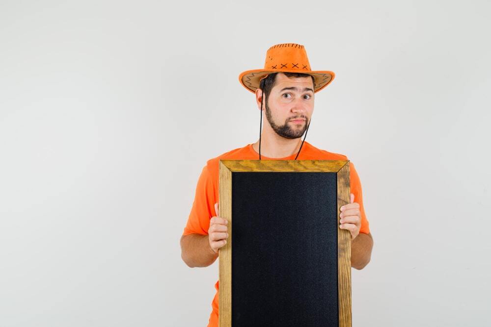 Tips for Effective Outdoor Signage Boards (A person standing confused holding an empty signage board)