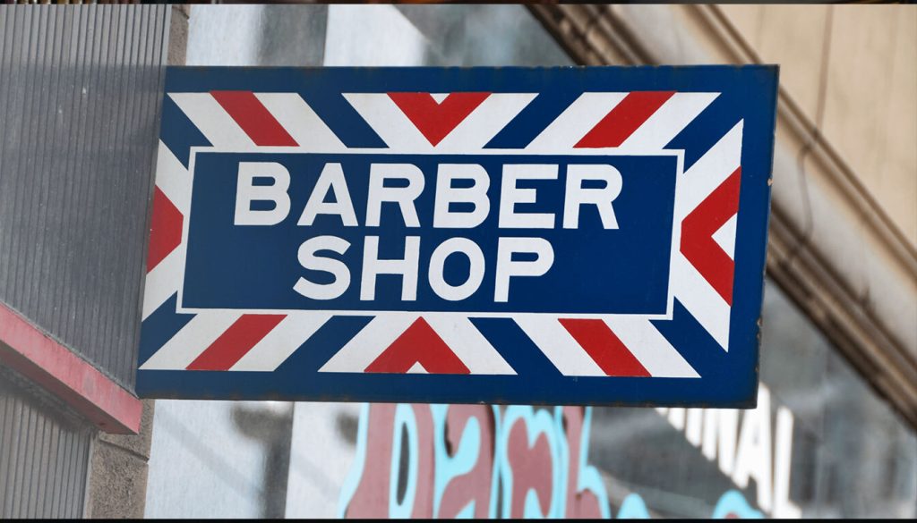 A classic barber shop sign featuring red, white, and blue stripes, indicating a place for haircuts and grooming services.