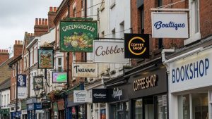 various outdoor signs mounted on buildings along a typical UK high street, with some signs being weathered and faded while some are new and fresh.